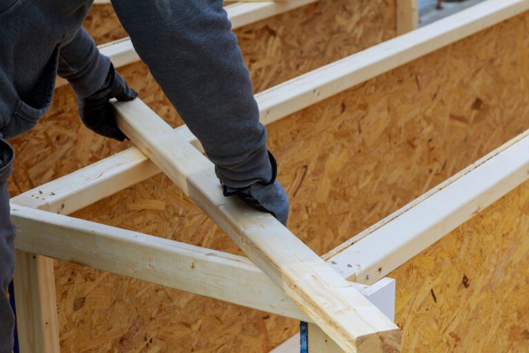 Closeup of a carpenter's hands on a construction site. Focus on drill and hand